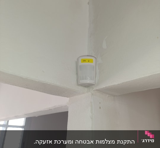 חיישן תנועה מותקן על קיר לבן בפינה
